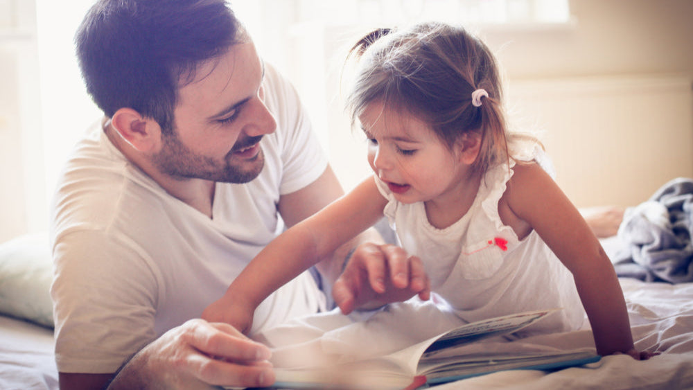 Ein Vater und seine Tochter lesen gemeinsam ein Buch, lernen und lachen dabei