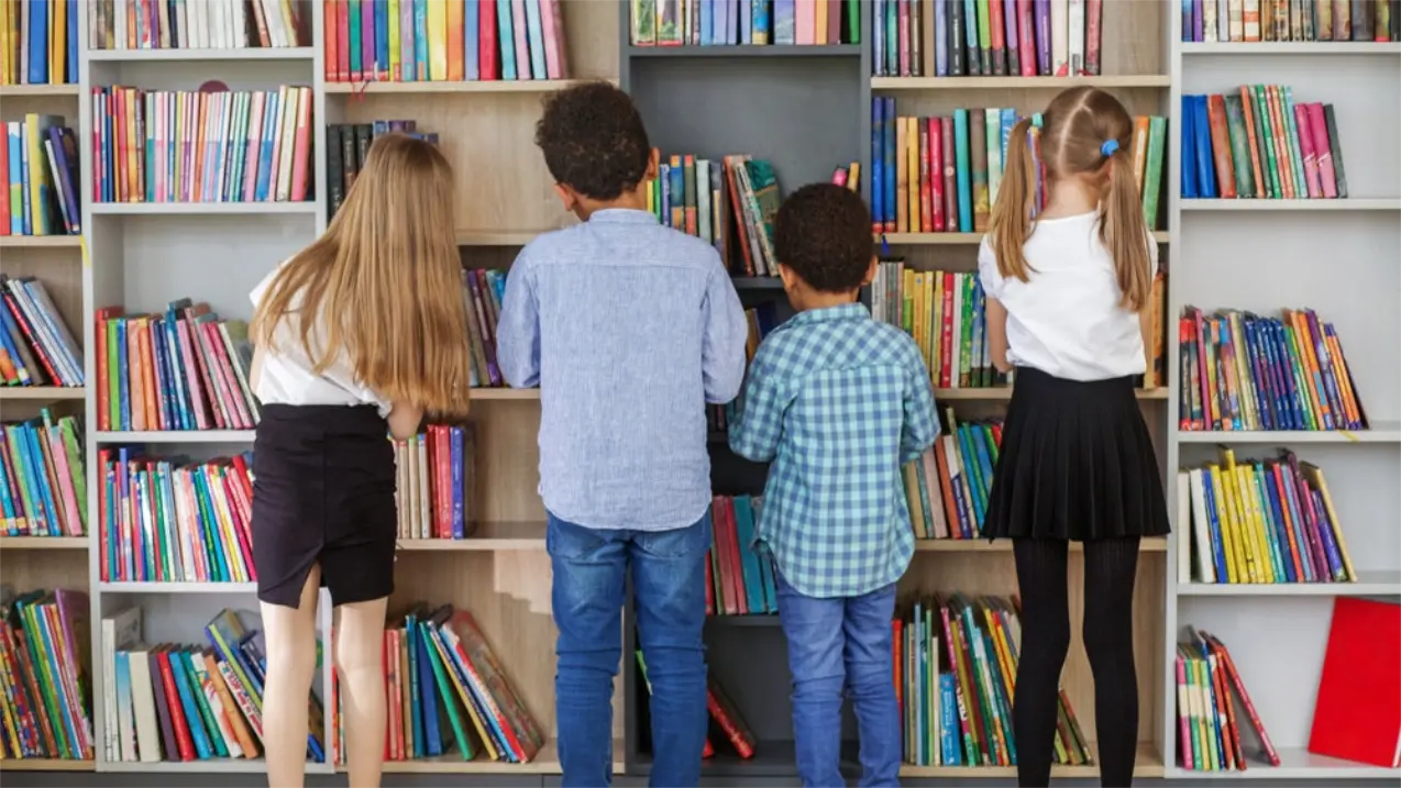 Kinder stöbern in einem großen Bücherregal