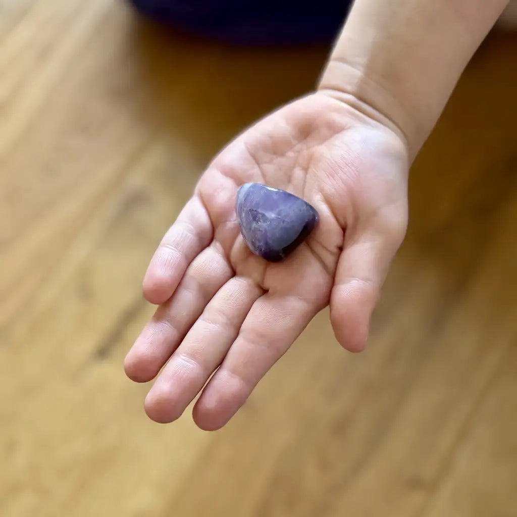 Ausgestreckte Kinderhand die einen Amethyst hält