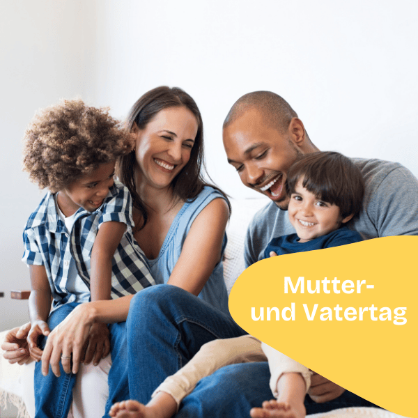 Eine glückliche vierköpfige Familie sitzt lächelnd und lachend auf einer Couch. Die Eltern halten ihre beiden Kinder auf dem Schoß. Eine gelbe Form in der Ecke zeigt den deutschen Text "Mutter- und Vatertag", der auf diesen besonderen Anlass hinweist.