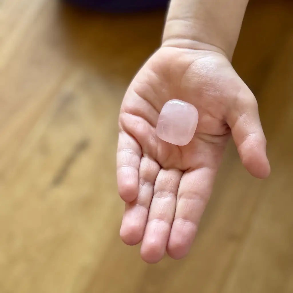 Ausgestreckte Kinderhand die einen Rosenquarz hält