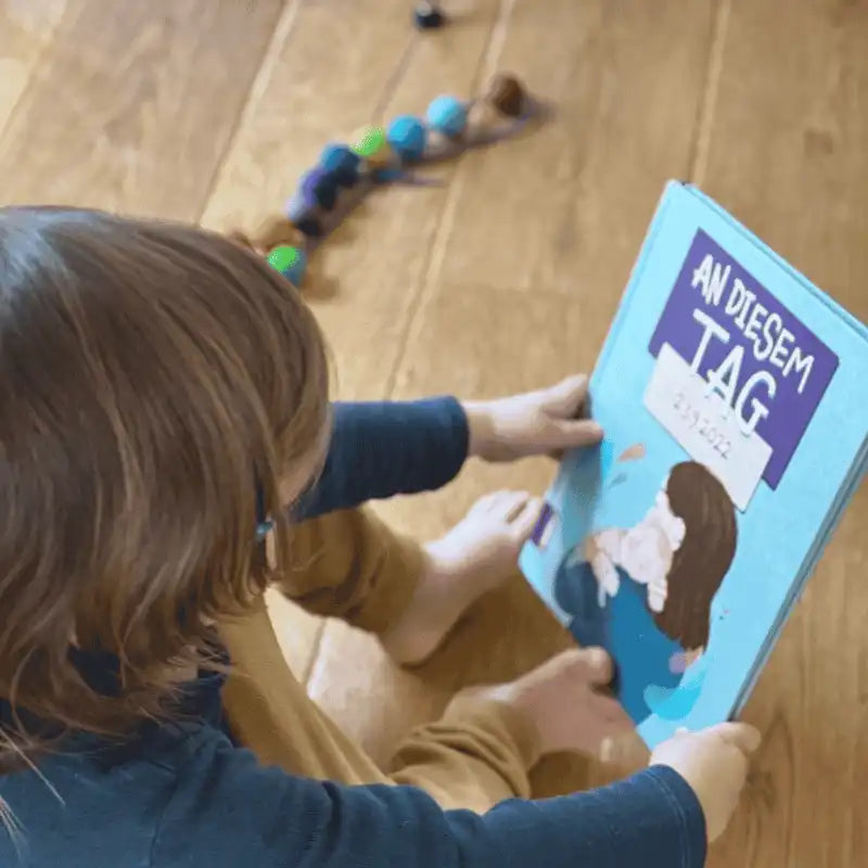 Kind hält das Buch An diesem Tag mit Händen und Füßen