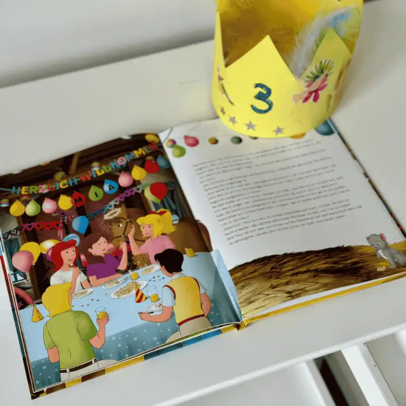 Pappkrone und aufgeschlagene Seite, auf der Bibi und Tina mit Mia Geburtstag feiern