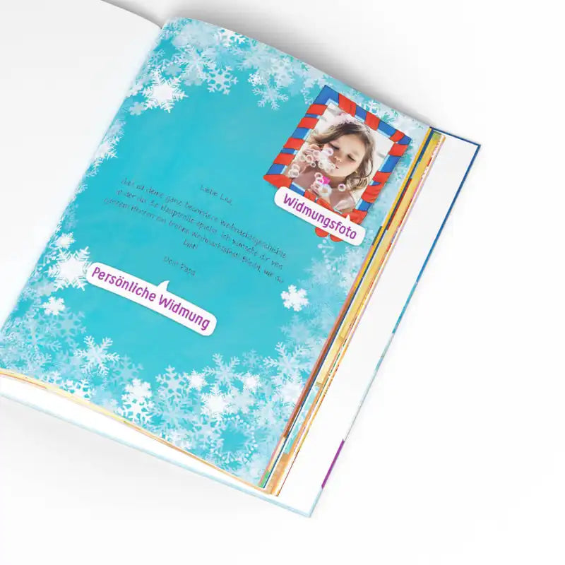 Ein aufgeschlagenes Buch aus "Dein Weihnachtsmärchen" von Framily zeigt eine blaue Seite mit weißen Schneeflocken, ein Kinderfoto oben rechts und einen deutschen Text mit den hervorgehobenen Bezeichnungen "Widmungsfoto" & "Persönliche Widmung" - perfekt als personalisiertes Weihnachtsbuch für Kinder.