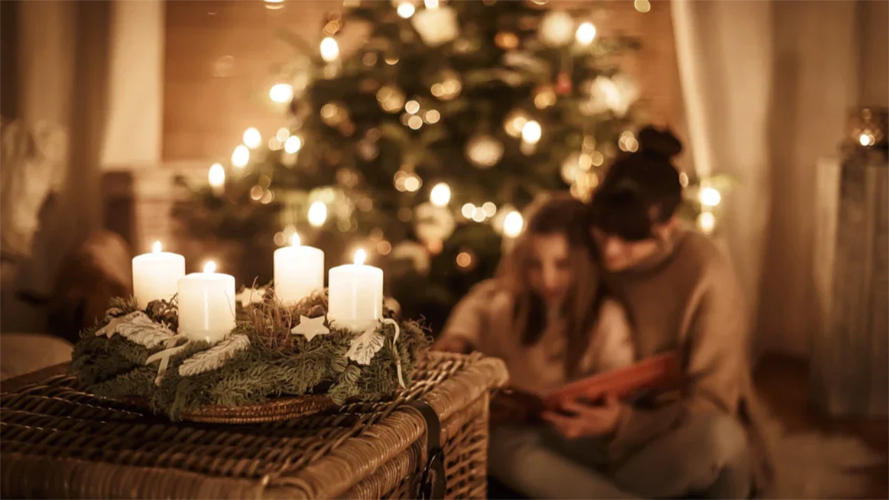 Mutter liest Tochter vor dem Weihnachtsbaum ein personalisiertes Buch vor
