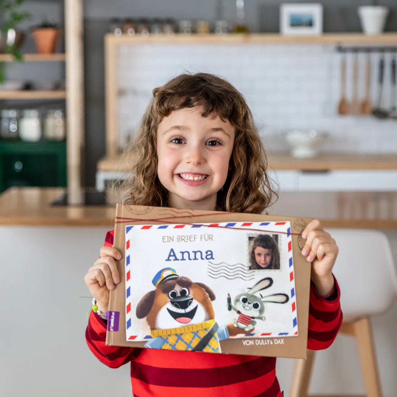 Ein Mädchen zeigt stolz sein personalisiertes Buch von Framily "Ein Brief für dich"